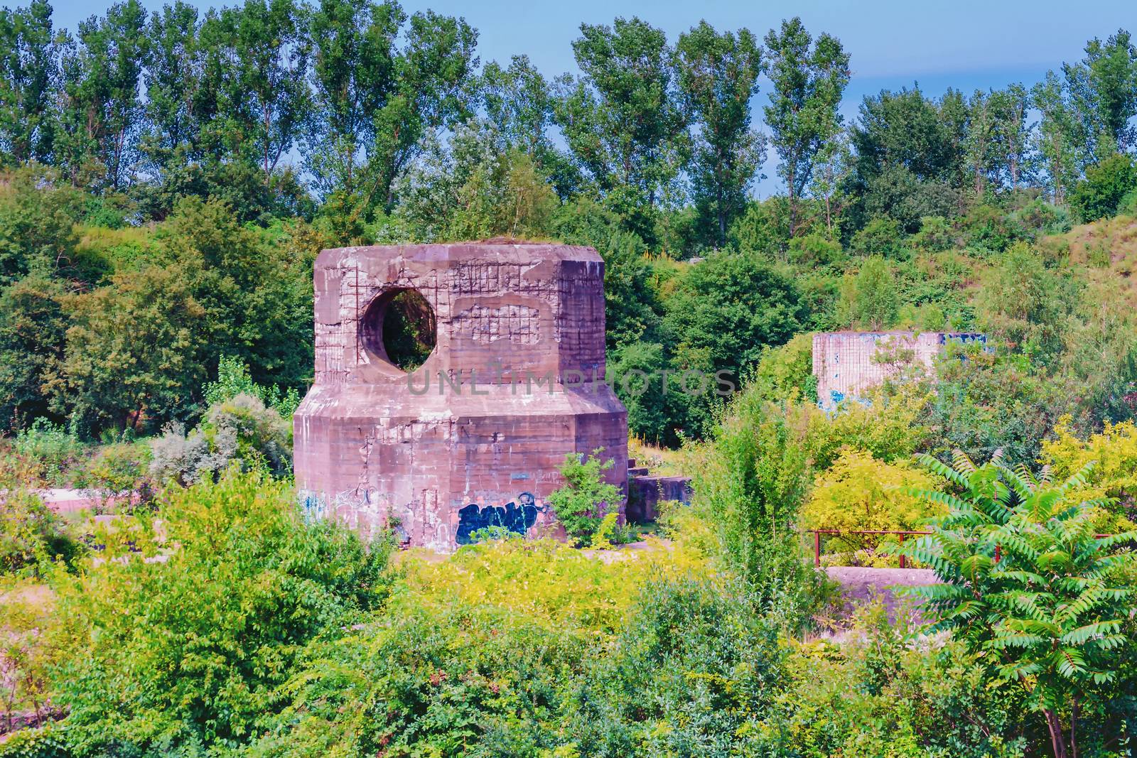 Age bomb shelter of an industrial plant with concrete block walls, archways and rusty steel.