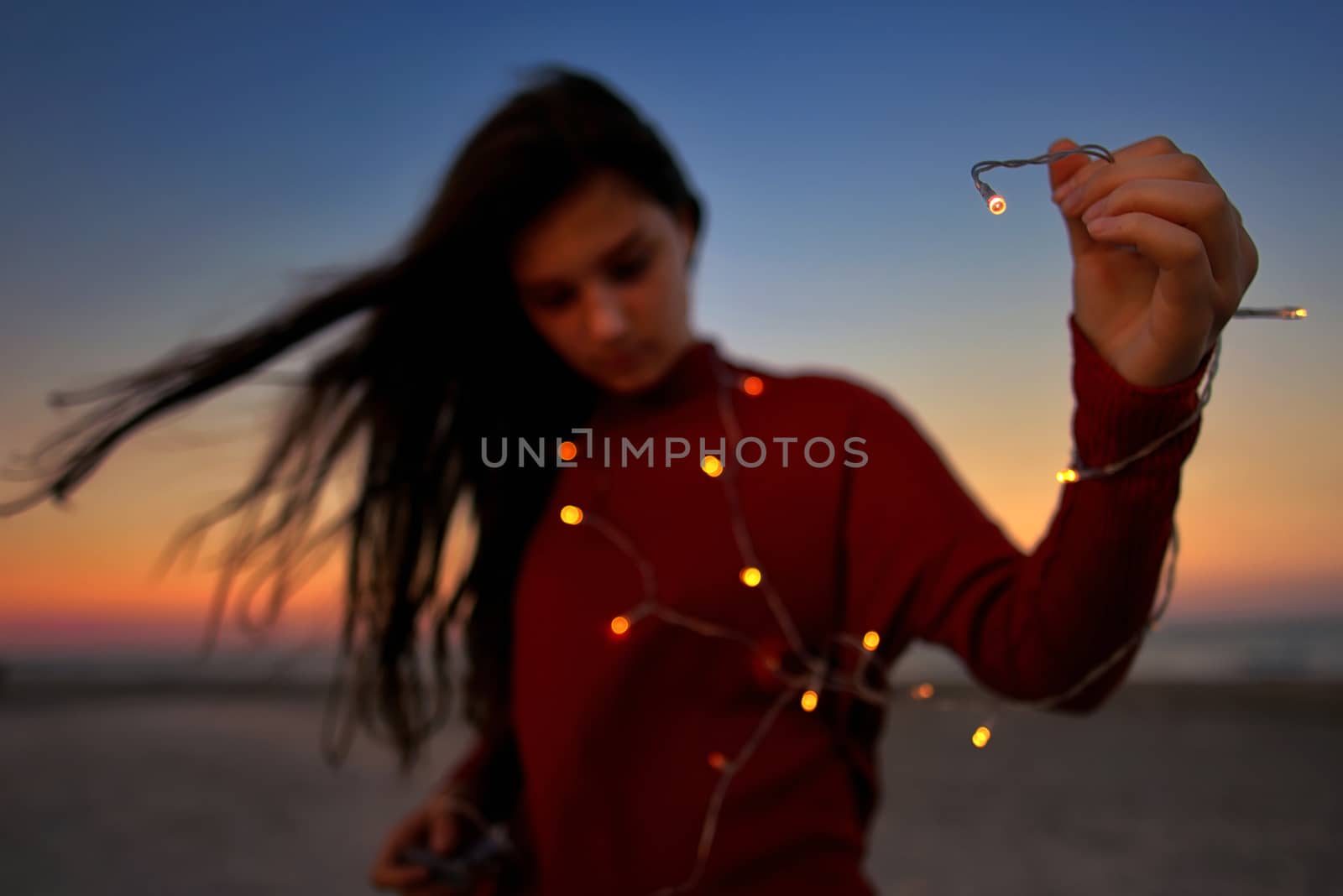 Teen girl with lights on beach in summer
