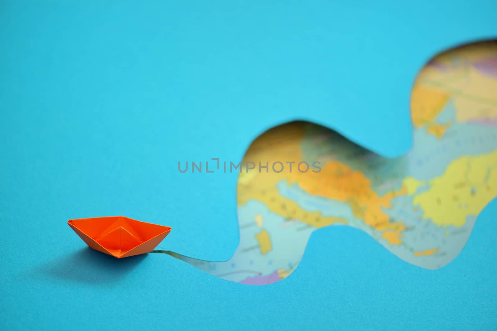 Paper boat making waves on a background map of the world