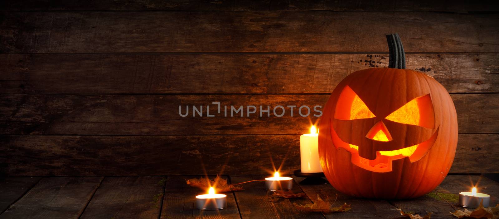 Halloween pumpkin head jack o lantern and candles on wooden background