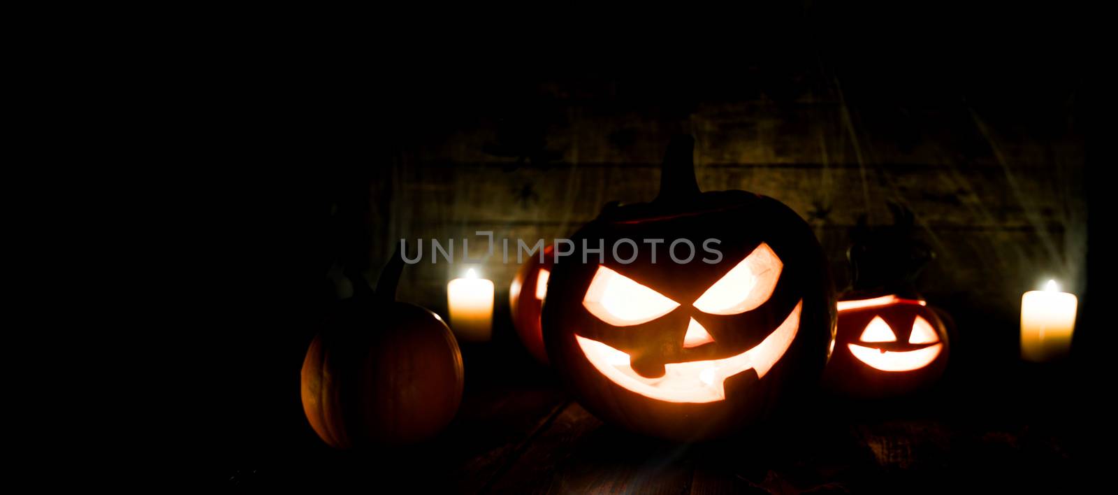 Jack O Lantern Halloween pumpkins, spiders on web and burning candles