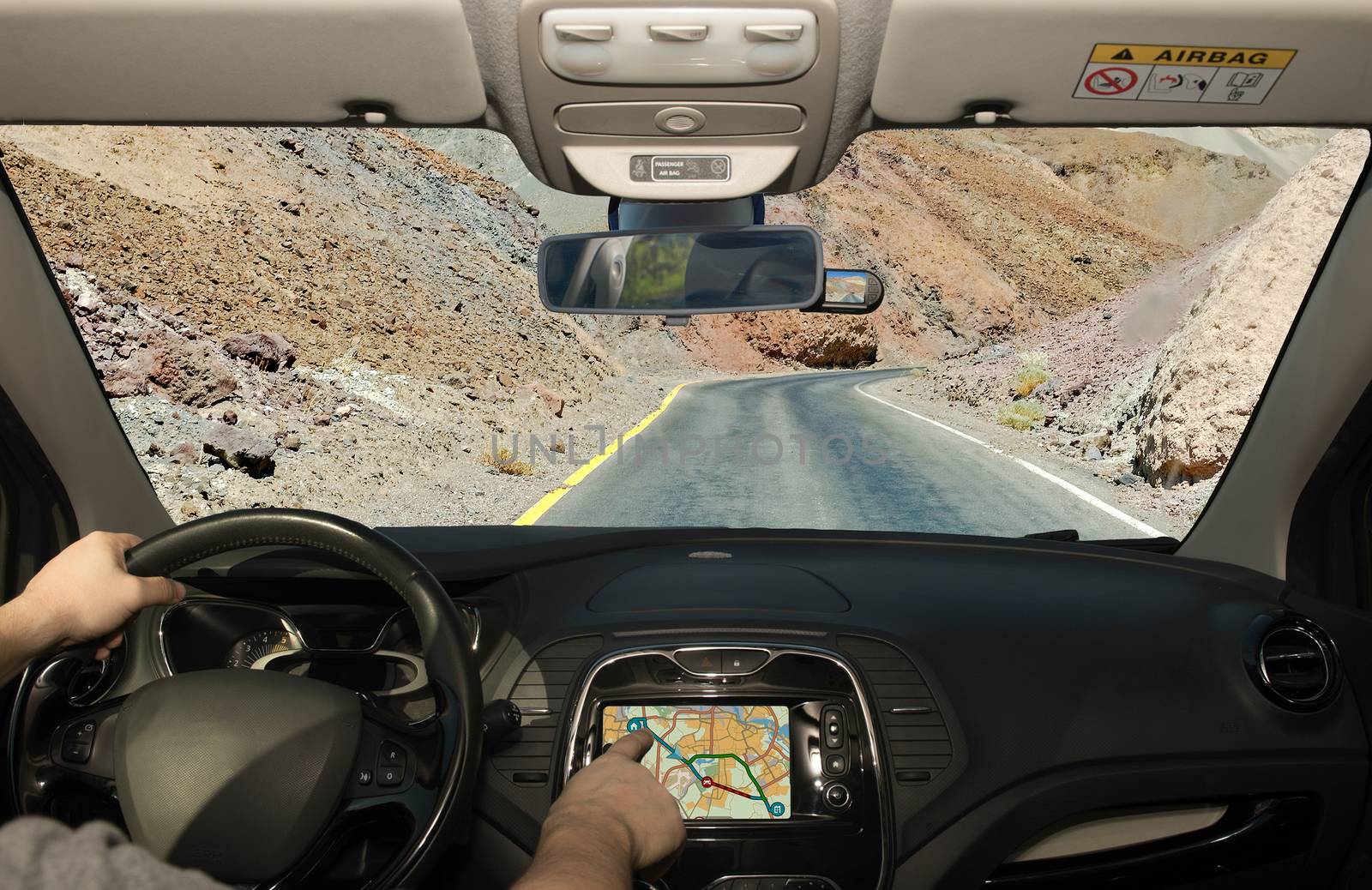 Driving a car while using the touch screen of a GPS navigation system towards a desert road, Death Valley, USA