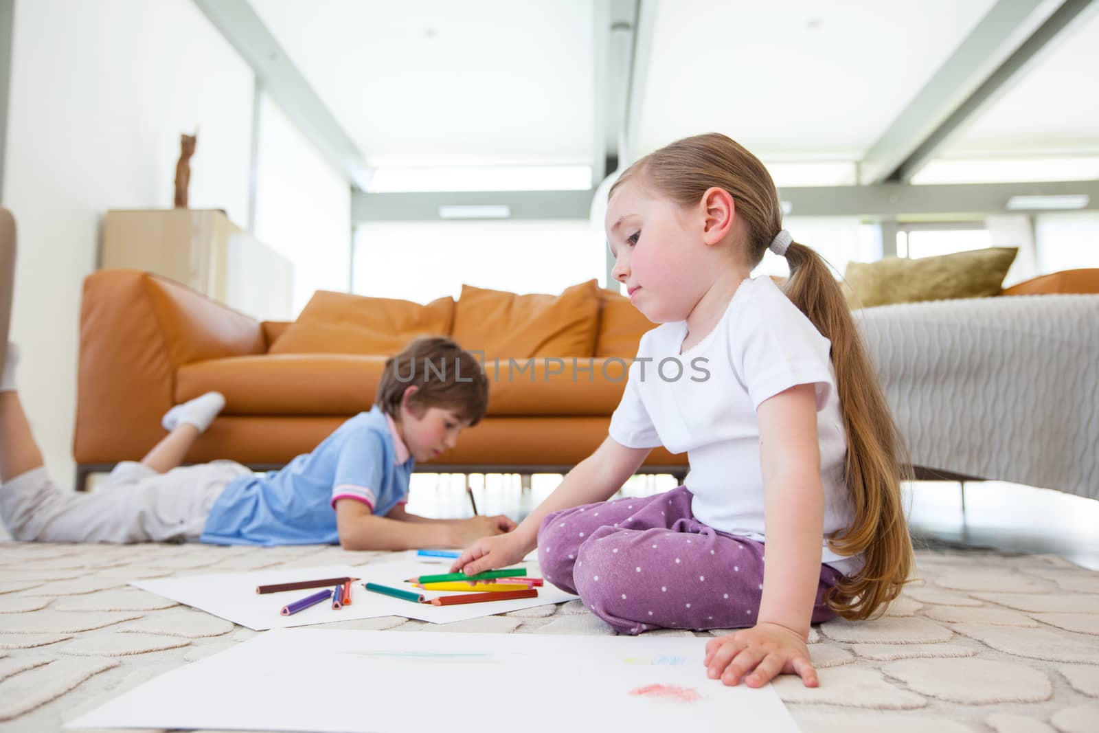 Little boy and girl drawing with color pencils on the floor playing together