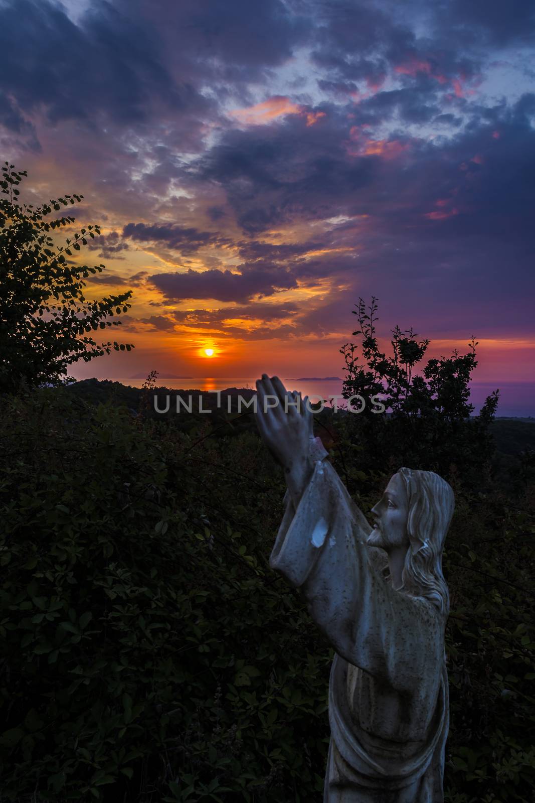 Jesus statue at a beautiful sunset at Corfu, Greece by ankarb