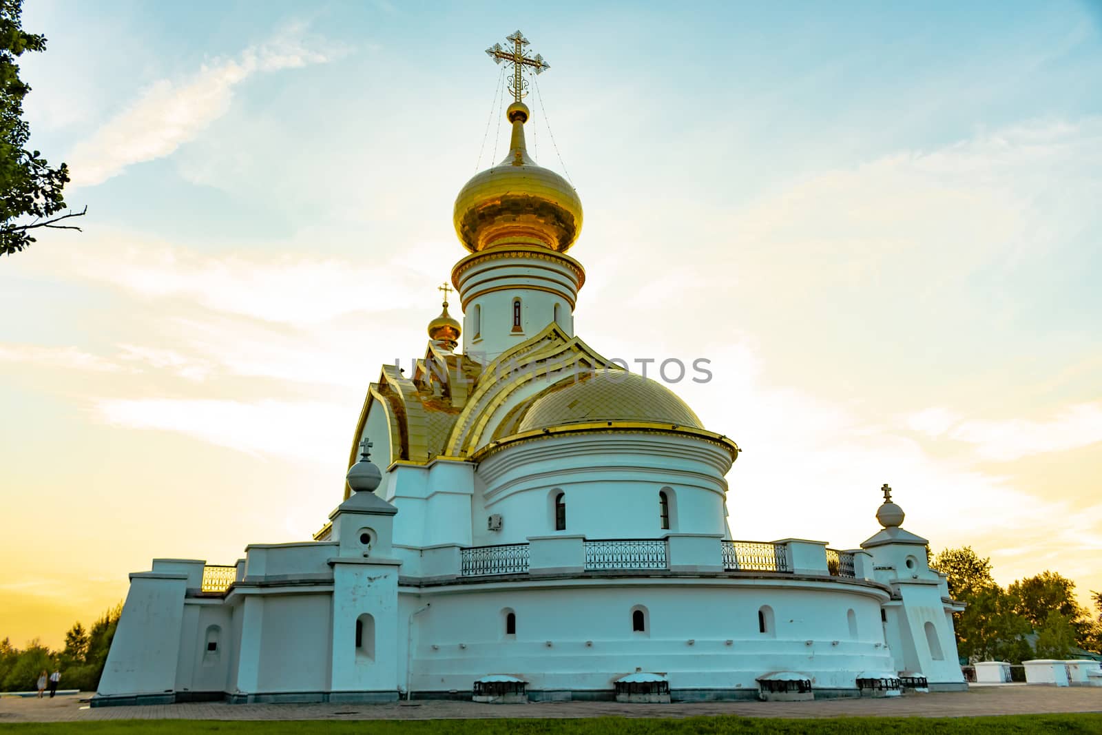 Beautiful view during sunset at the temple of St. Seraphim of Sarov in the city of Khabarovsk. A beautiful green lawn in the foreground. Religious architecture, buildings and traditions. Russia.