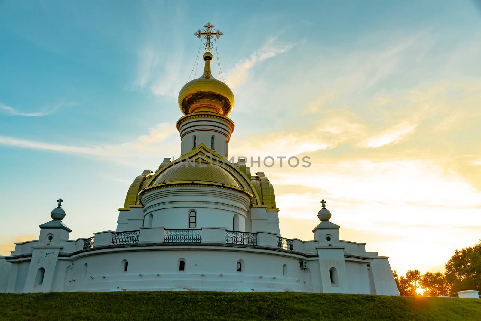 Beautiful view during sunset at the temple of St. Seraphim of Sarov in the city of Khabarovsk. A beautiful green lawn in the foreground. Religious architecture, buildings and traditions. Russia.