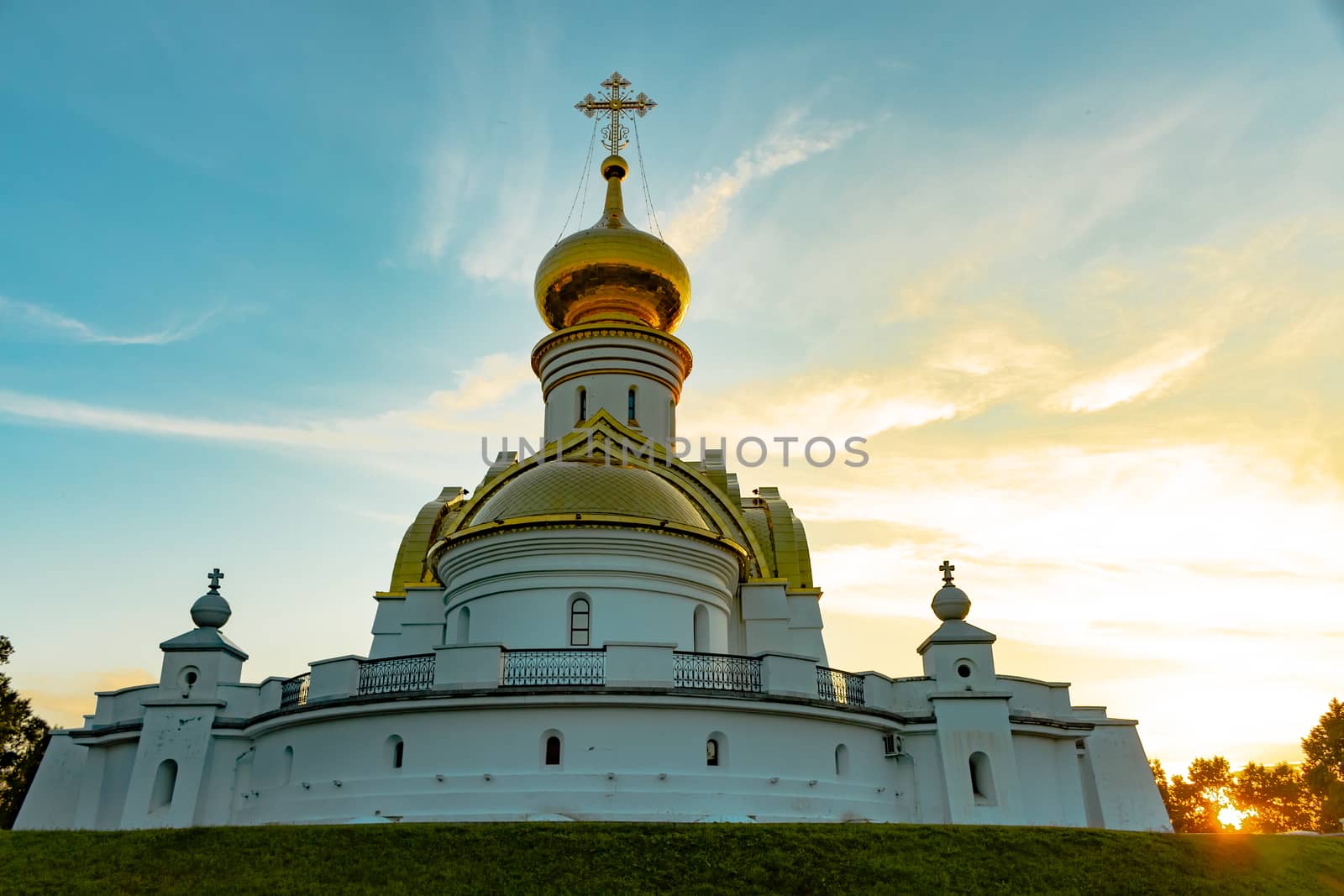 Beautiful view during sunset at the temple of St. Seraphim of Sarov in the city of Khabarovsk. A beautiful green lawn in the foreground. Religious architecture, buildings and traditions. Russia.