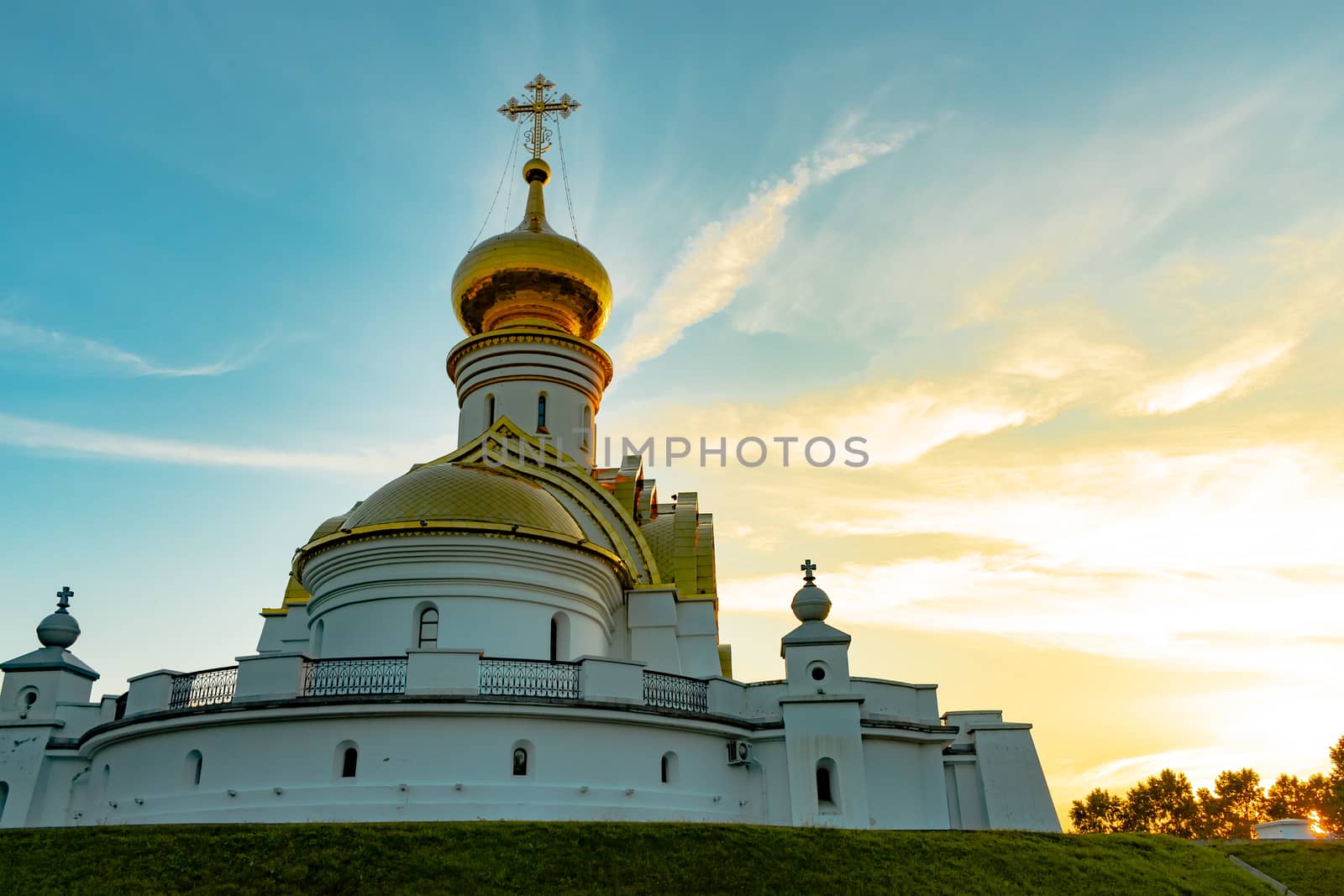 Beautiful view during sunset at the temple of St. Seraphim of Sarov in the city of Khabarovsk. A beautiful green lawn in the foreground. Religious architecture, buildings and traditions. Russia.