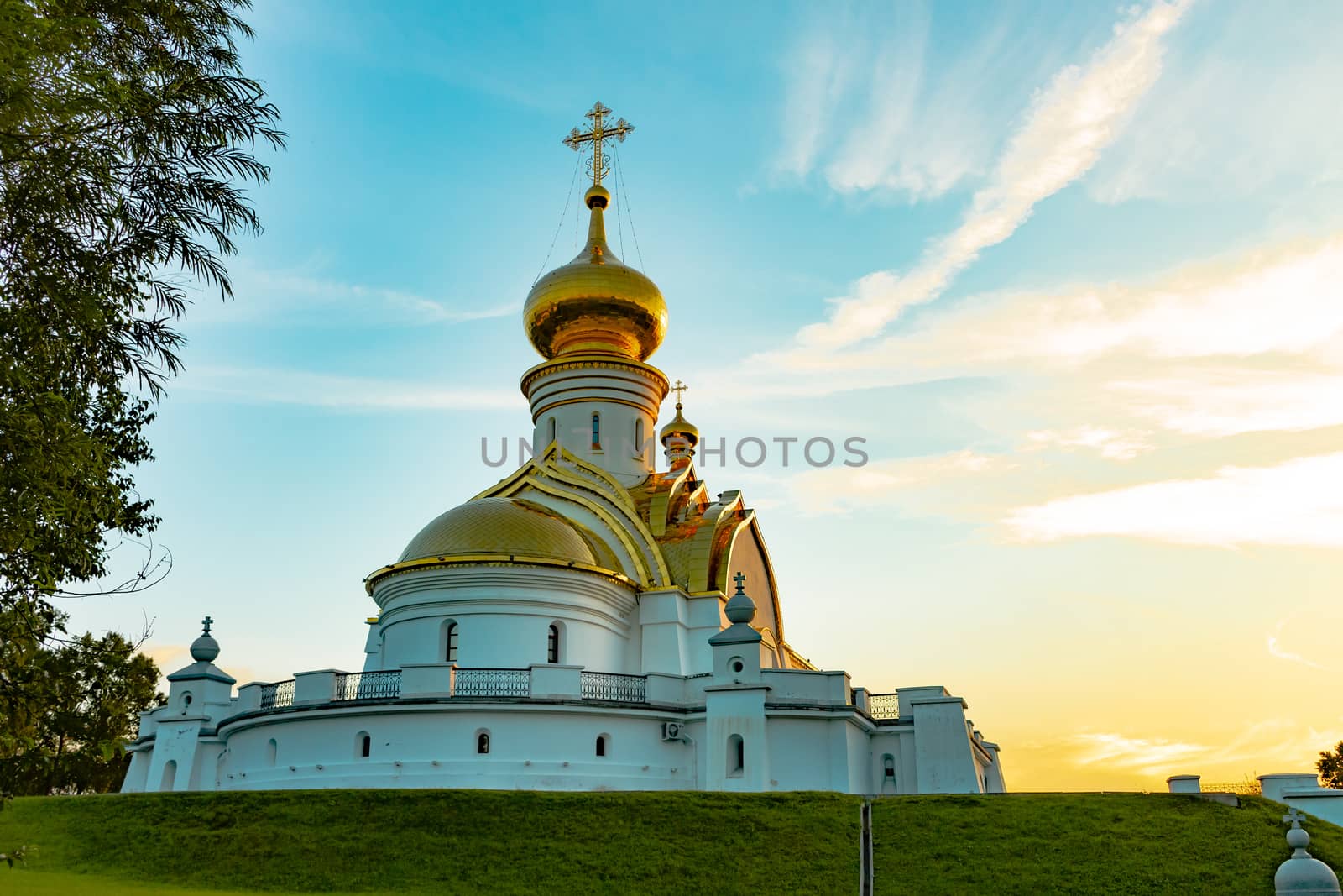 Beautiful view during sunset at the temple of St. Seraphim of Sarov in the city of Khabarovsk. A beautiful green lawn in the foreground. Religious architecture, buildings and traditions. Russia.