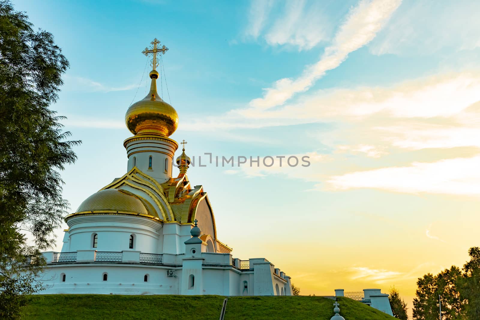 Beautiful view during sunset at the temple of St. Seraphim of Sarov in the city of Khabarovsk. A beautiful green lawn in the foreground. Religious architecture, buildings and traditions. Russia.