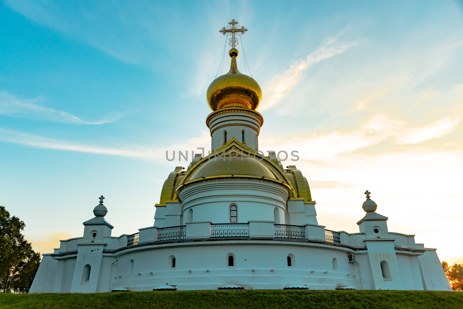 Beautiful view during sunset at the temple of St. Seraphim of Sarov in the city of Khabarovsk. A beautiful green lawn in the foreground. Religious architecture, buildings and traditions. Russia.