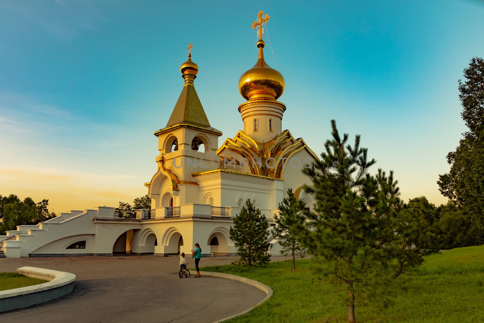 Beautiful view during sunset at the temple of St. Seraphim of Sarov in the city of Khabarovsk. A beautiful green lawn in the foreground. Religious architecture, buildings and traditions. Russia.