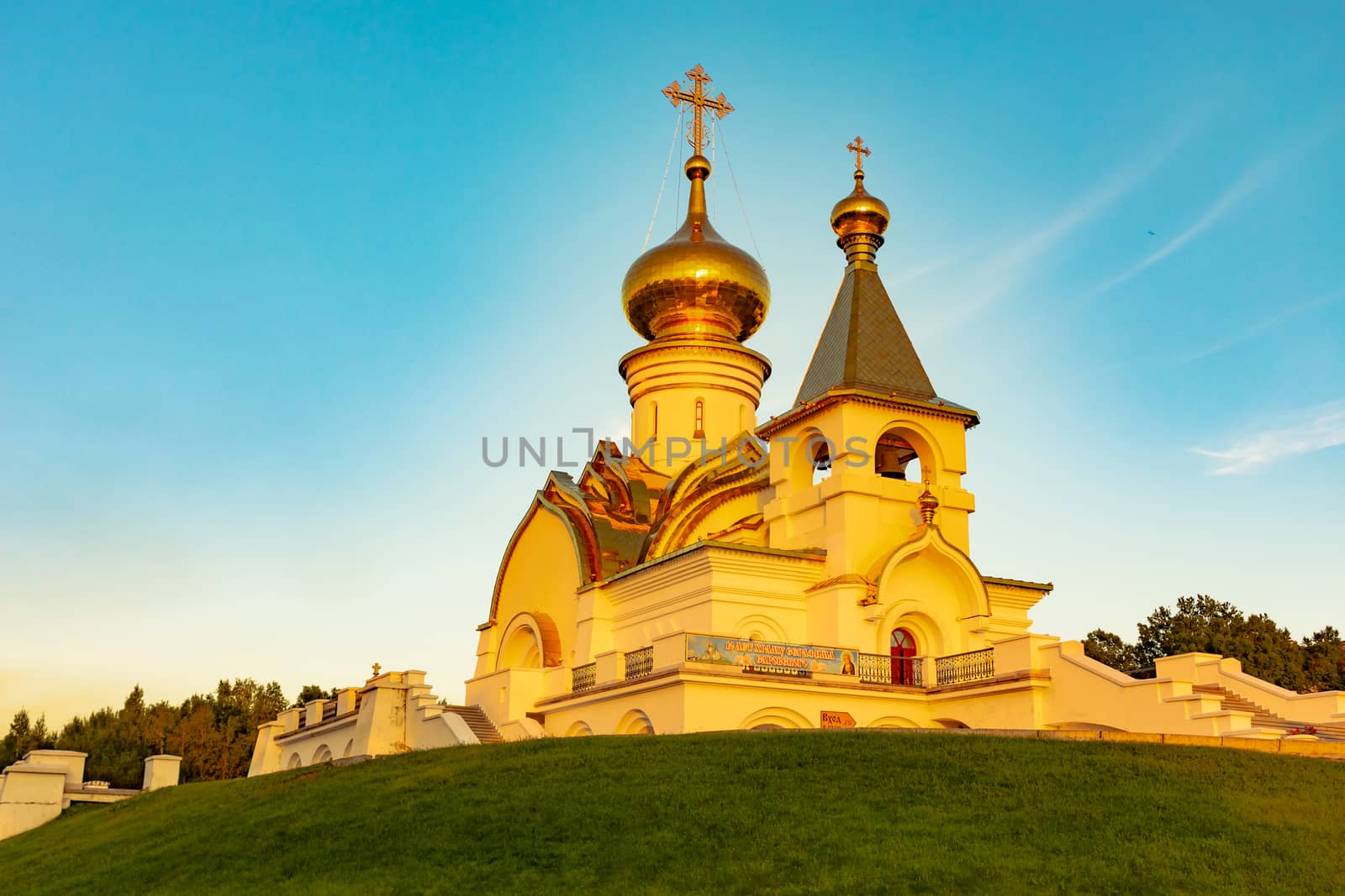 Beautiful view during sunset at the temple of St. Seraphim of Sarov in the city of Khabarovsk. A beautiful green lawn in the foreground. Religious architecture, buildings and traditions. Russia.