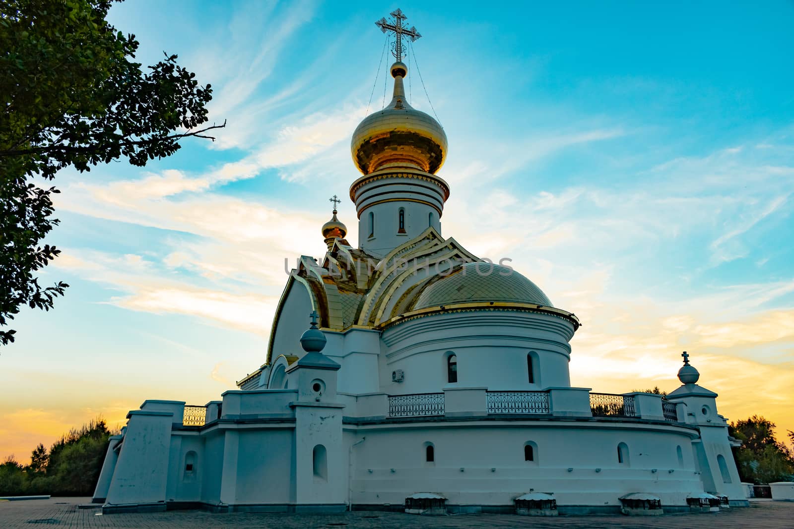 Beautiful view during sunset at the temple of St. Seraphim of Sarov in the city of Khabarovsk. A beautiful green lawn in the foreground. Religious architecture, buildings and traditions. Russia.
