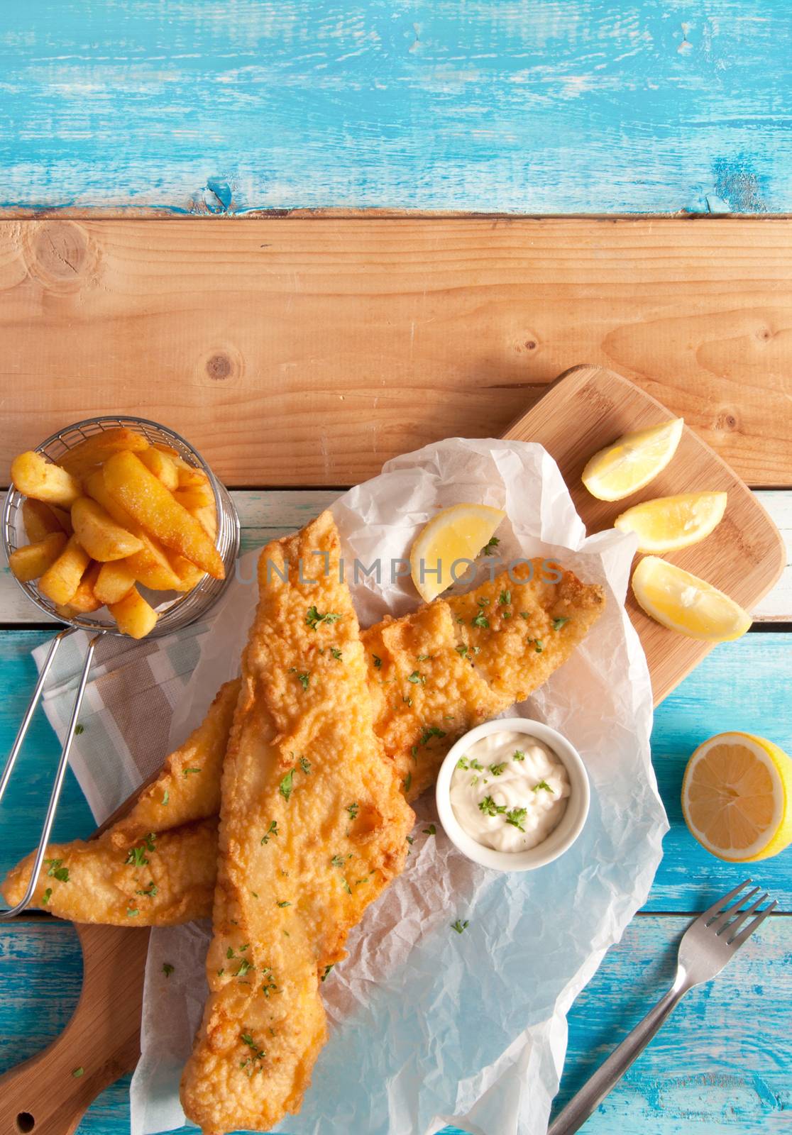 Two pieces of fried fish in batter with chips in a serving basket 