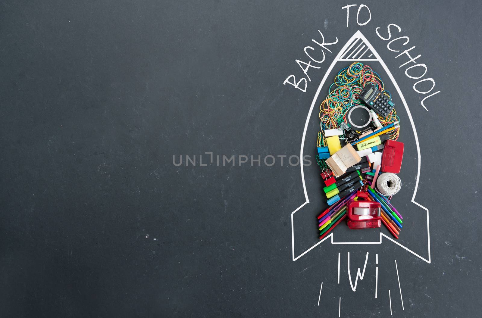 Back to school sketch of a rocket icon with stationery accessories on a chalkboard