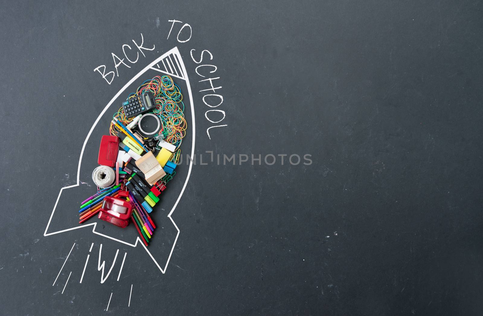 Back to school sketch of a rocket icon with stationery accessories on a chalkboard