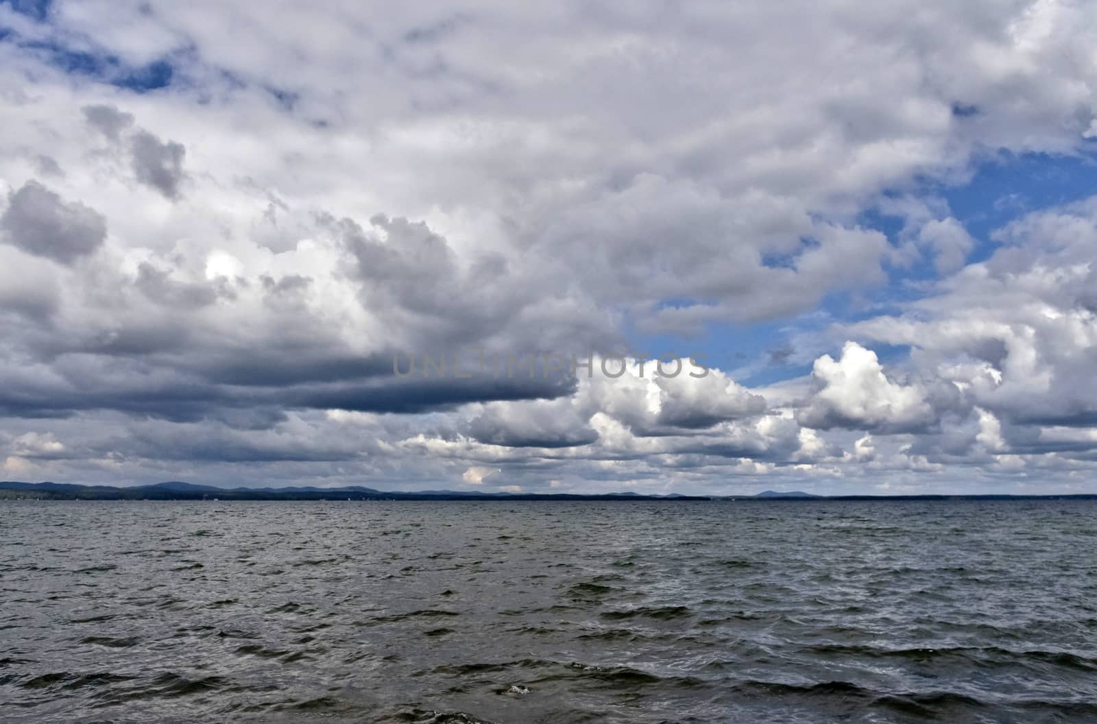 day lake in gray-white cloudy weather, South Ural, Uvildy, in the distance are seen the Ural mountains