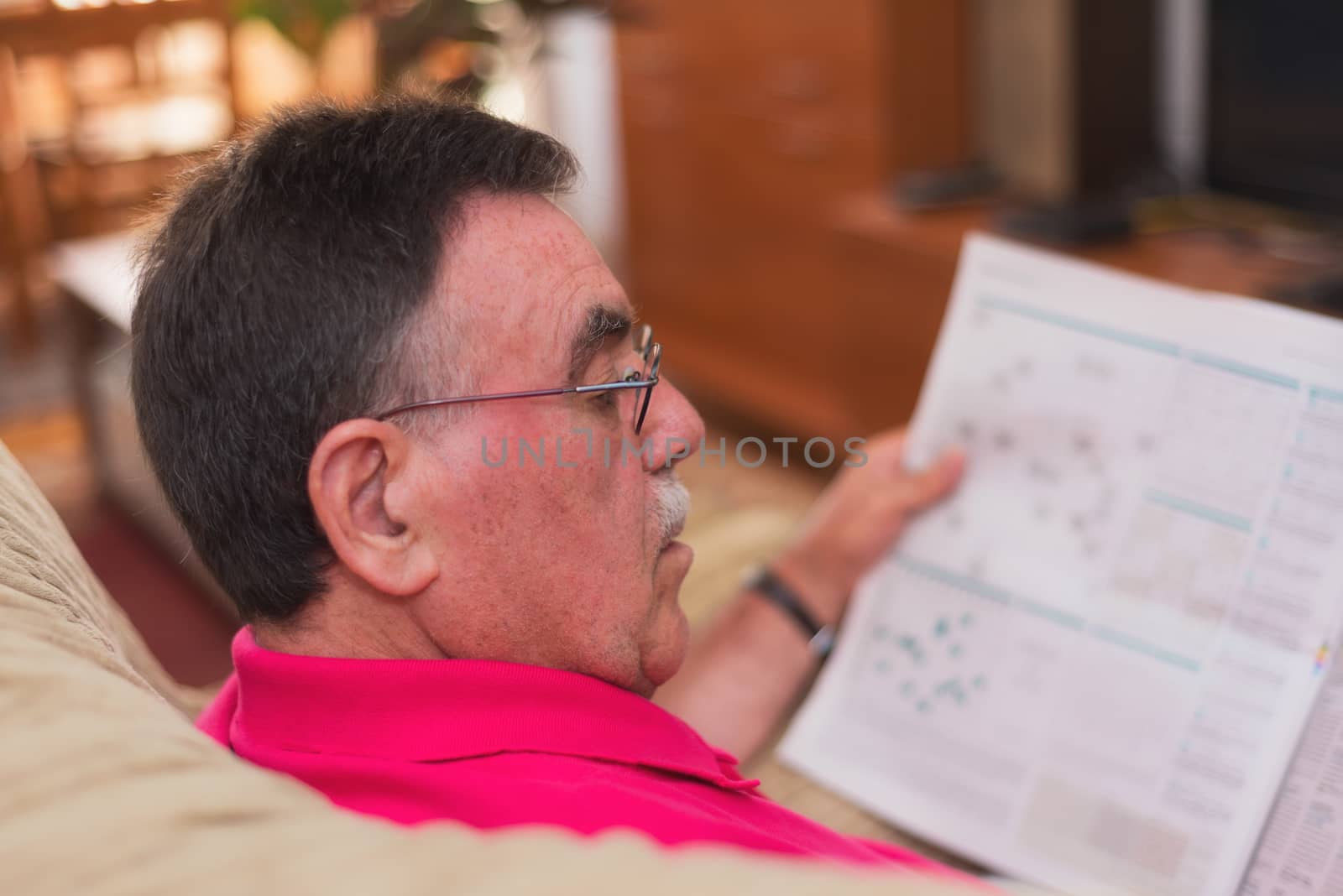 Portrait of a senior man reading newspaper by HERRAEZ