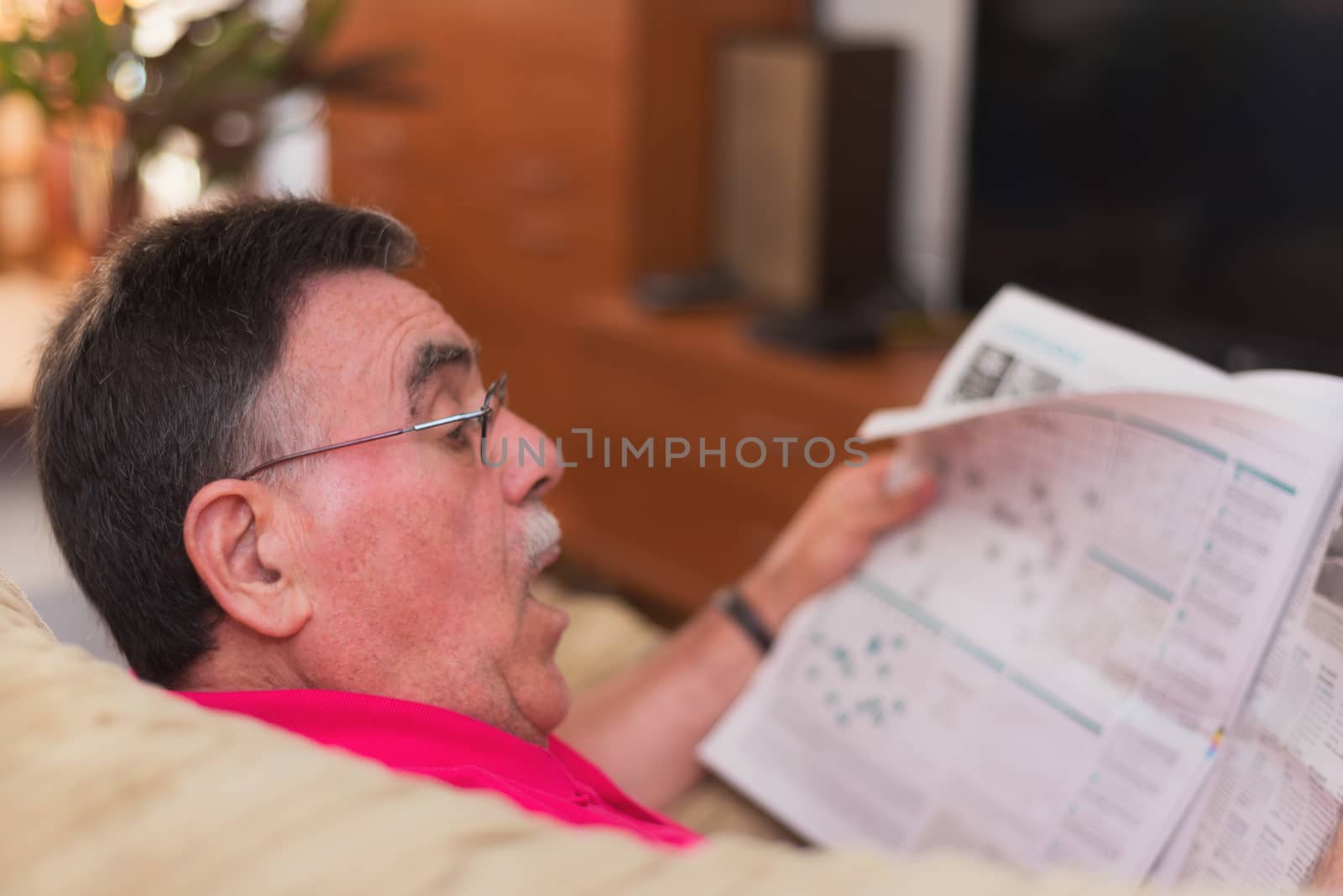 Portrait of a senior man reading newspaper by HERRAEZ