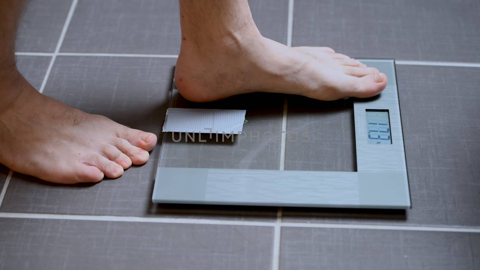 Male feet on glass scales, men's diet, body weight, close up, man stepping up on scales, side view