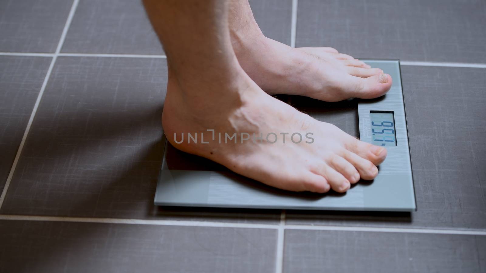 Male feet on glass scales, men's diet, body weight, close up, man standing on scale