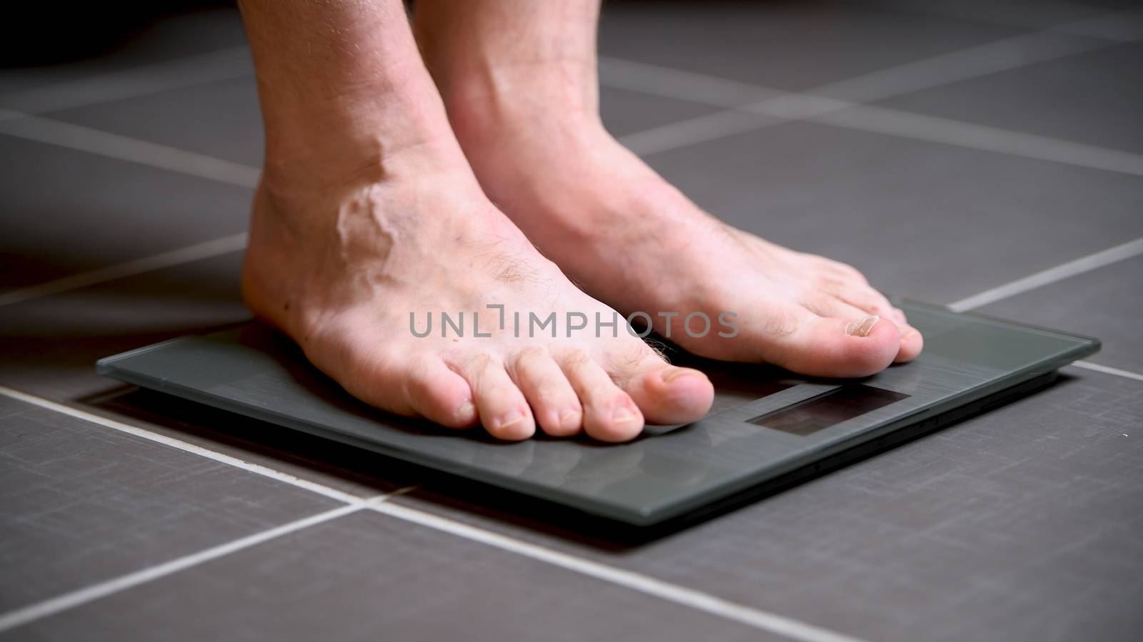 Male feet on glass scales, men's diet, body weight, close up