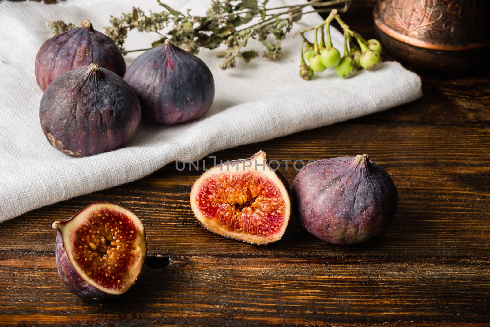 Ripe seasonal figs on the cloth and wooden surface with sliced one