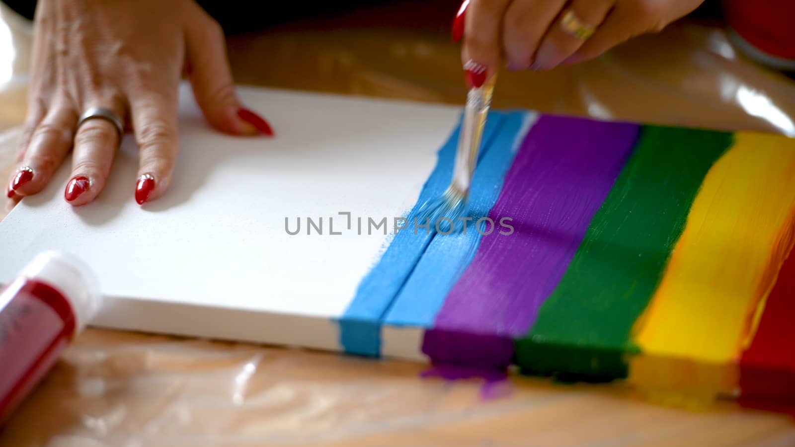 Female artist painting a rainbow with acrylic colors on canvas, hoe made art, DIY tutorial, colorful