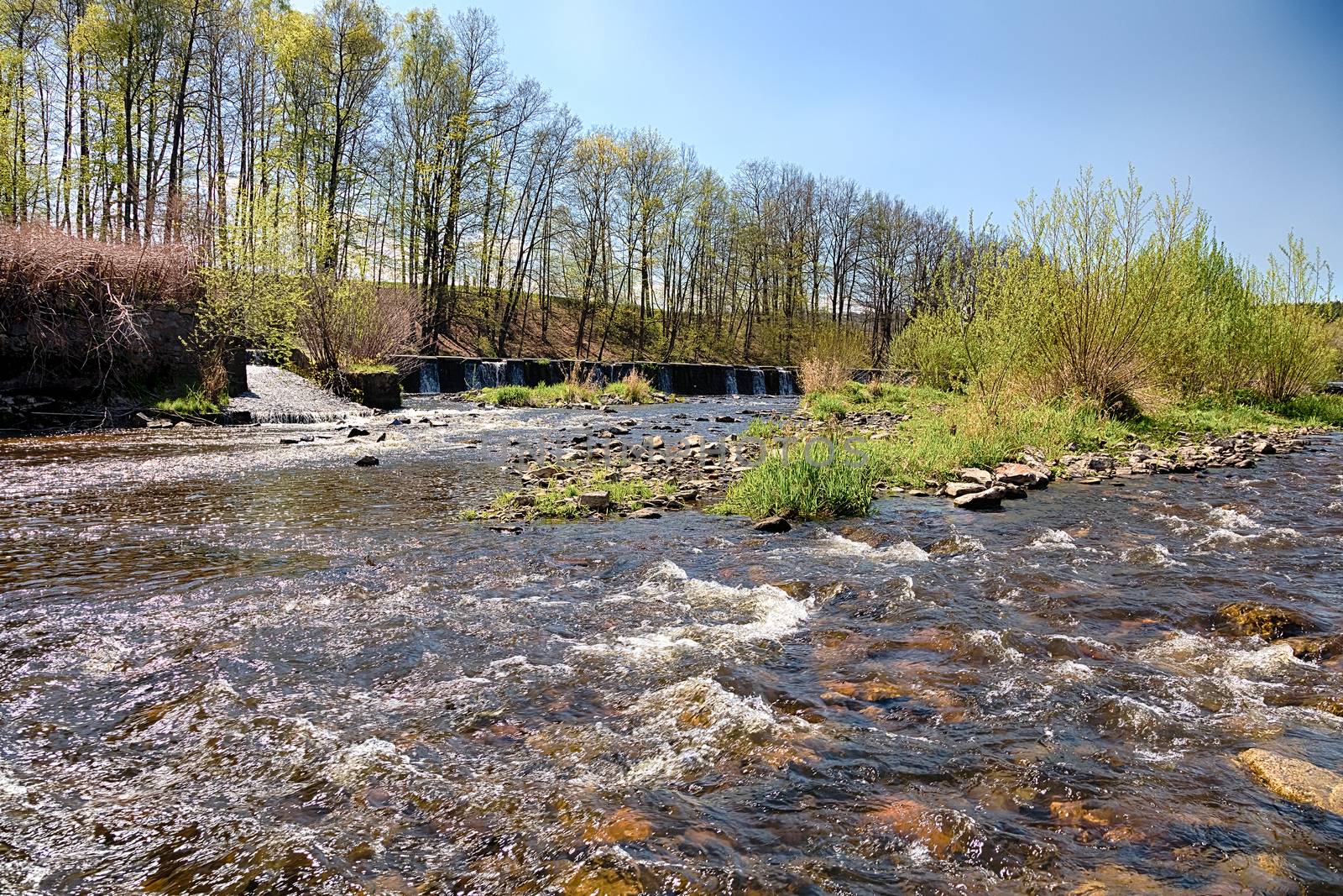 River with the weir runs over boulders