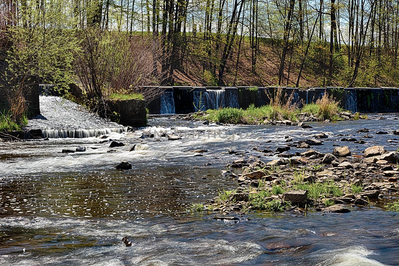 River with the weir runs over boulders