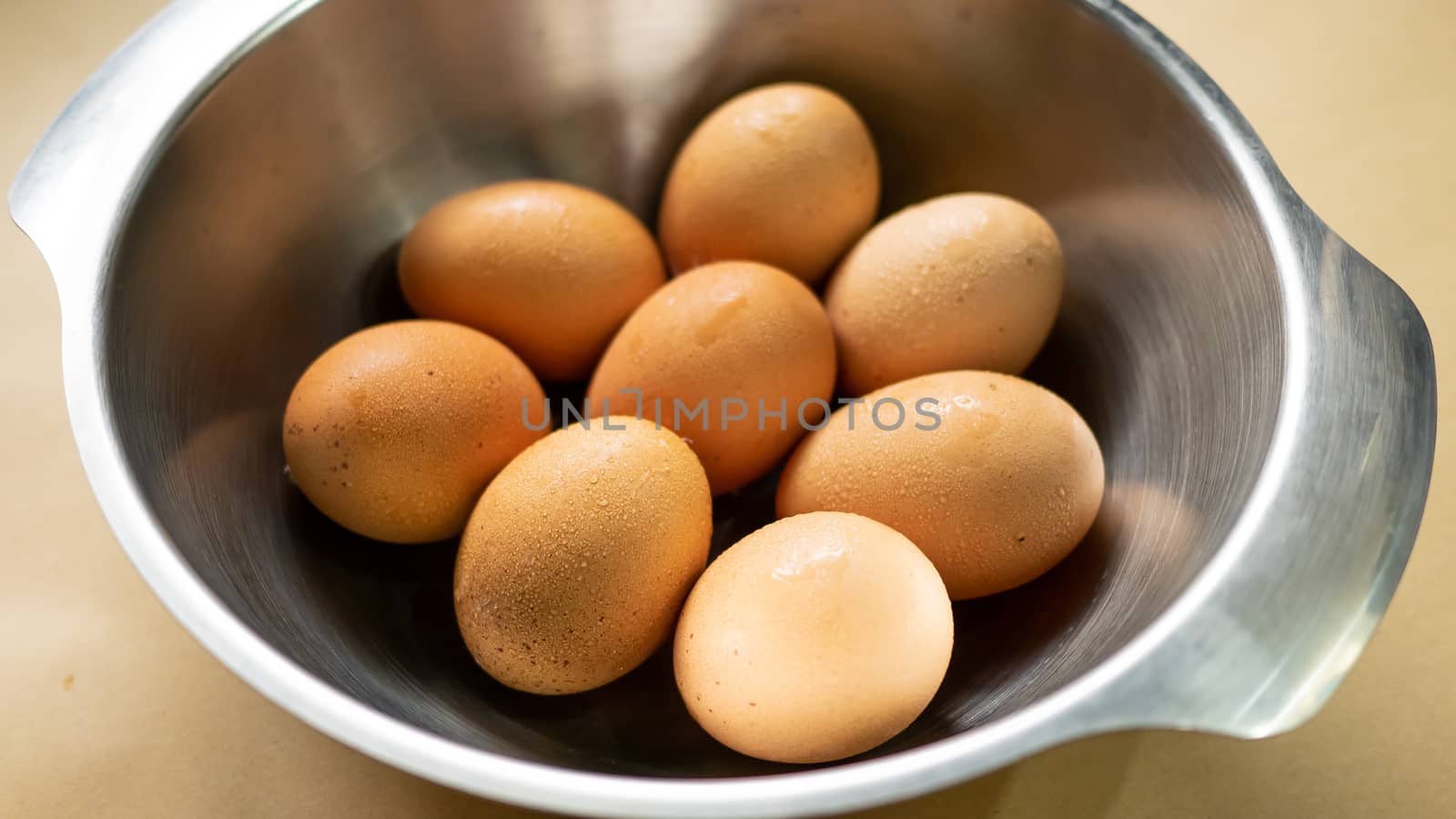 The close up of Fresh eggs in the stainless bowl.