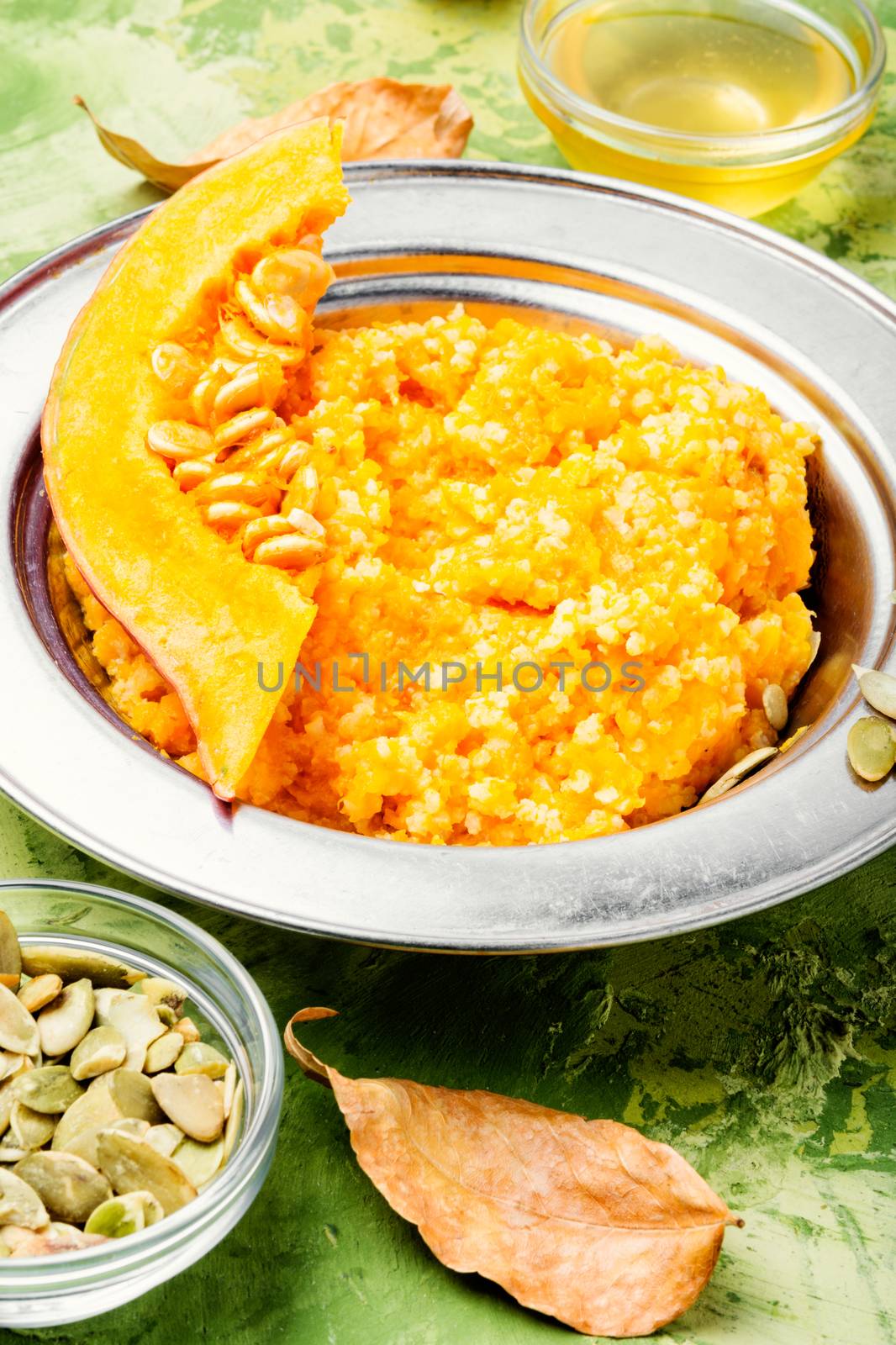 Homemade tasty porridge with orange pumpkin on green background