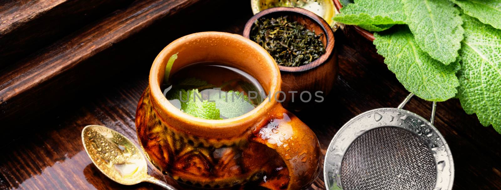 Brewed delicious herbal tea with sage on retro background