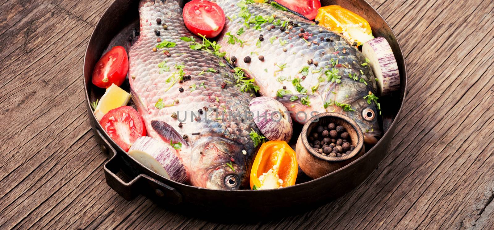 Fresh fish with ingredients for cooking on pan