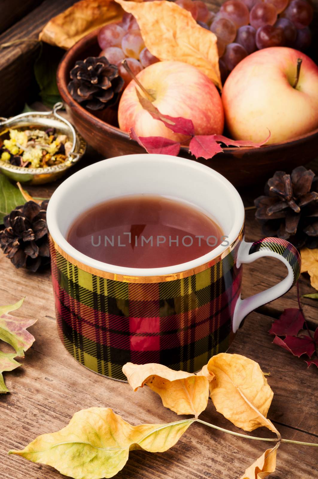 Cup with tea on an autumn background of fallen leaves, apples and grapes.Autumn still life