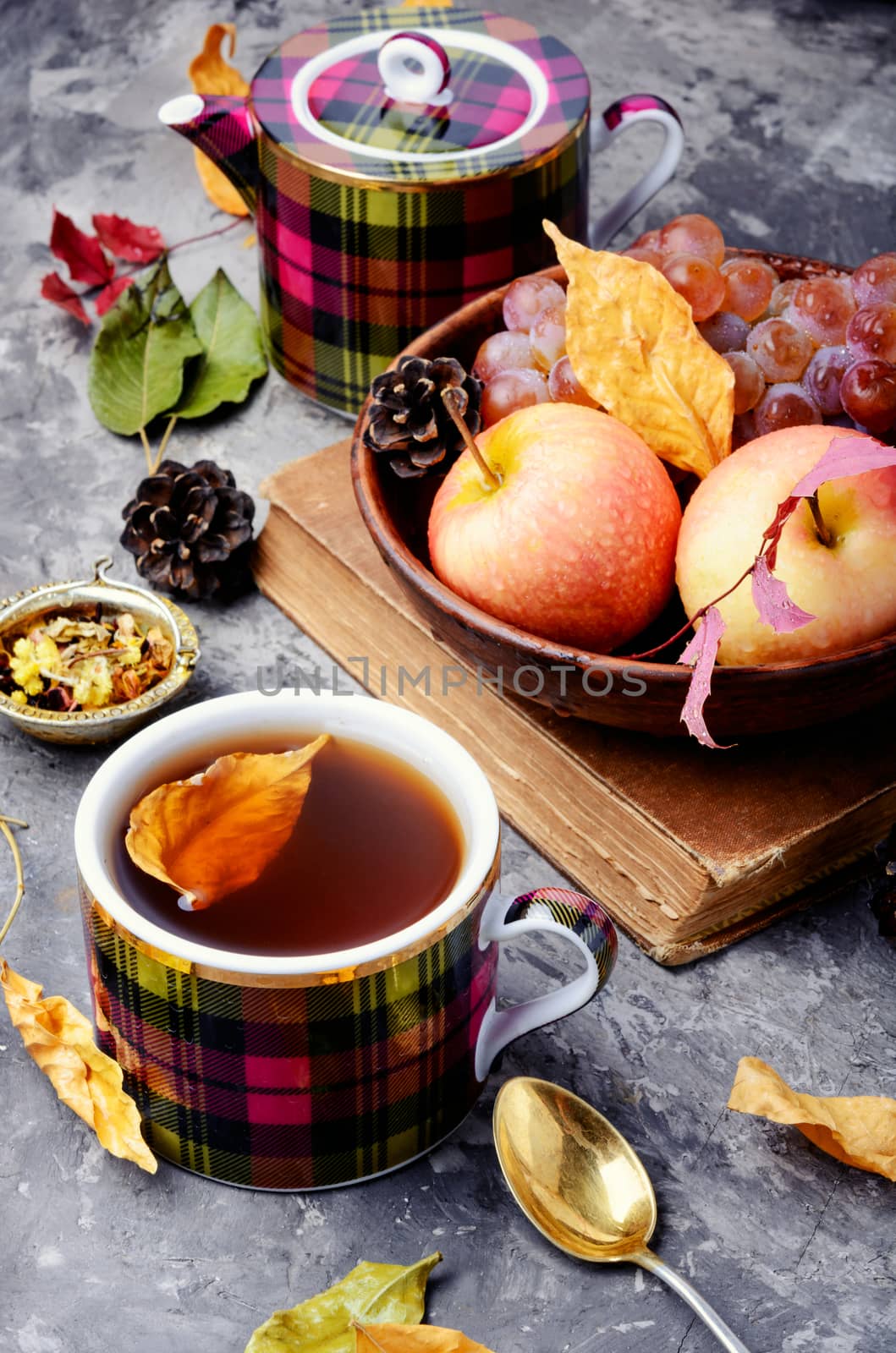 Cup with tea on an autumn background of fallen leaves, apples and grapes.Autumn still life