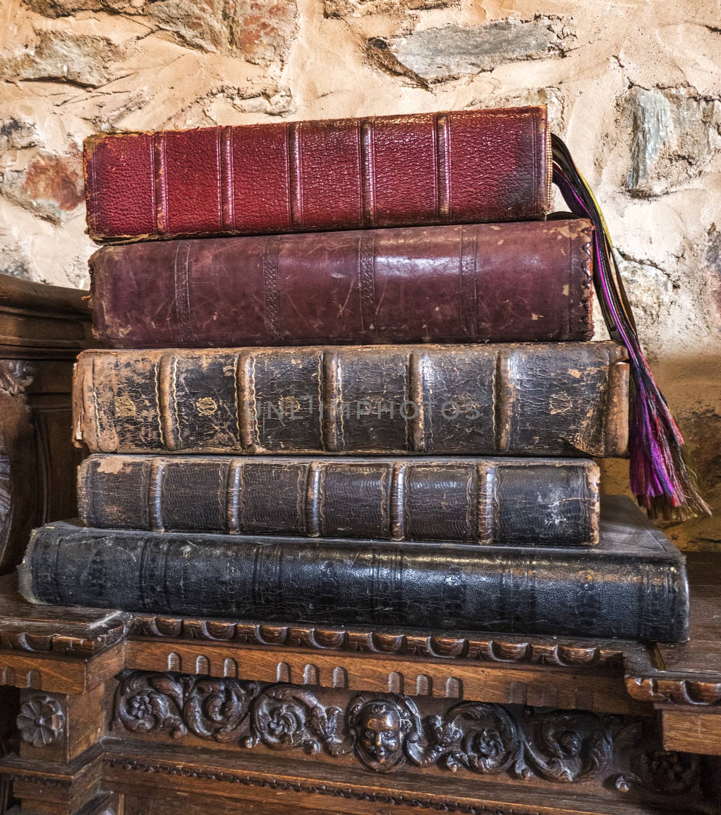 a pile of very old books on a wooden carved cabinet