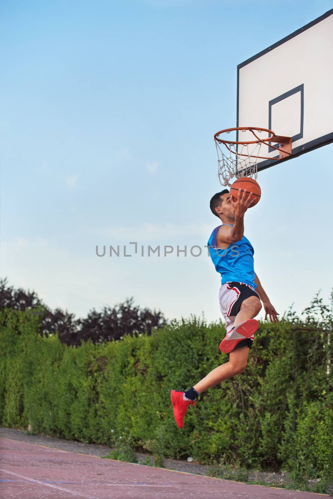 Basketball street player making a slam dunk by HERRAEZ