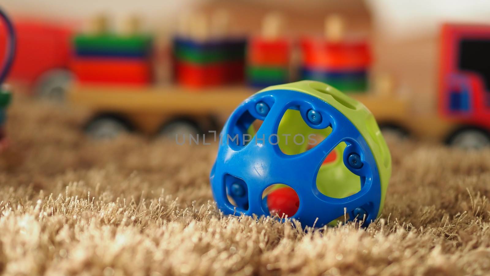 Many colorful baby wood toys on light brown color carpet which include ball, airplane, bus and others that helps development baby's EQ and IQ and make baby have a joyful moments.