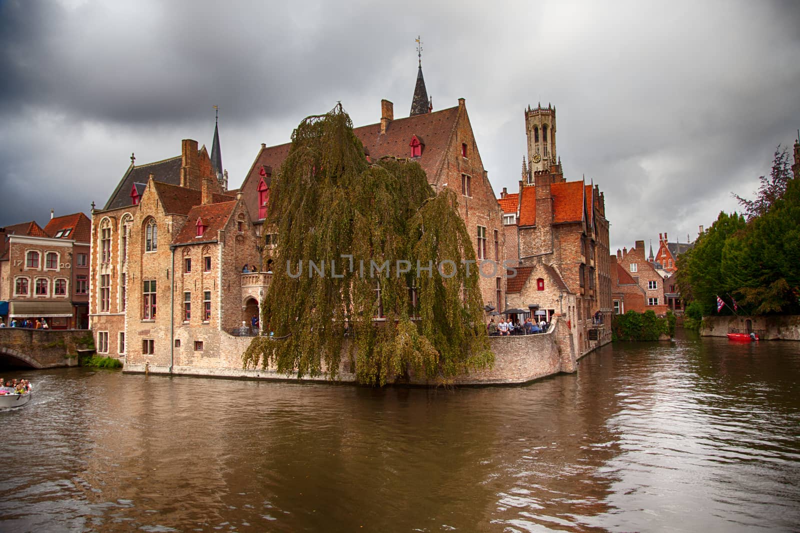BRUGES, BELGIUM - SEPTEMBER 05, 2018: Canal in Bruges and famous Belfry tower on the background in a beautiful autumn day, Belgium on September 05, 2018