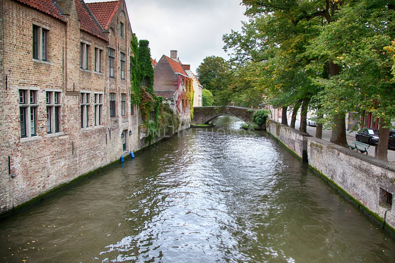 BRUGES, BELGIUM - SEPTEMBER 05, 2018: Canal in Bruges and famous Belfry tower on the background in a beautiful autumn day, Belgium on September 05, 2018