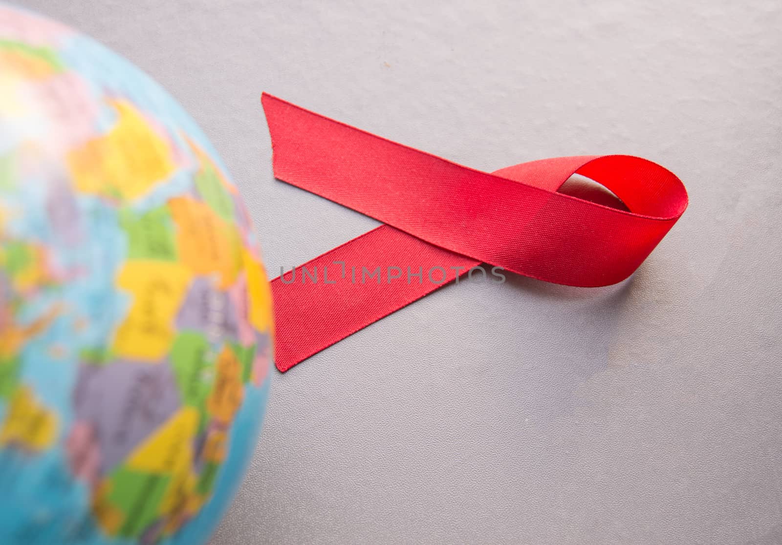 World AIDS day 1 December, close-up of world globe with red ribbon.