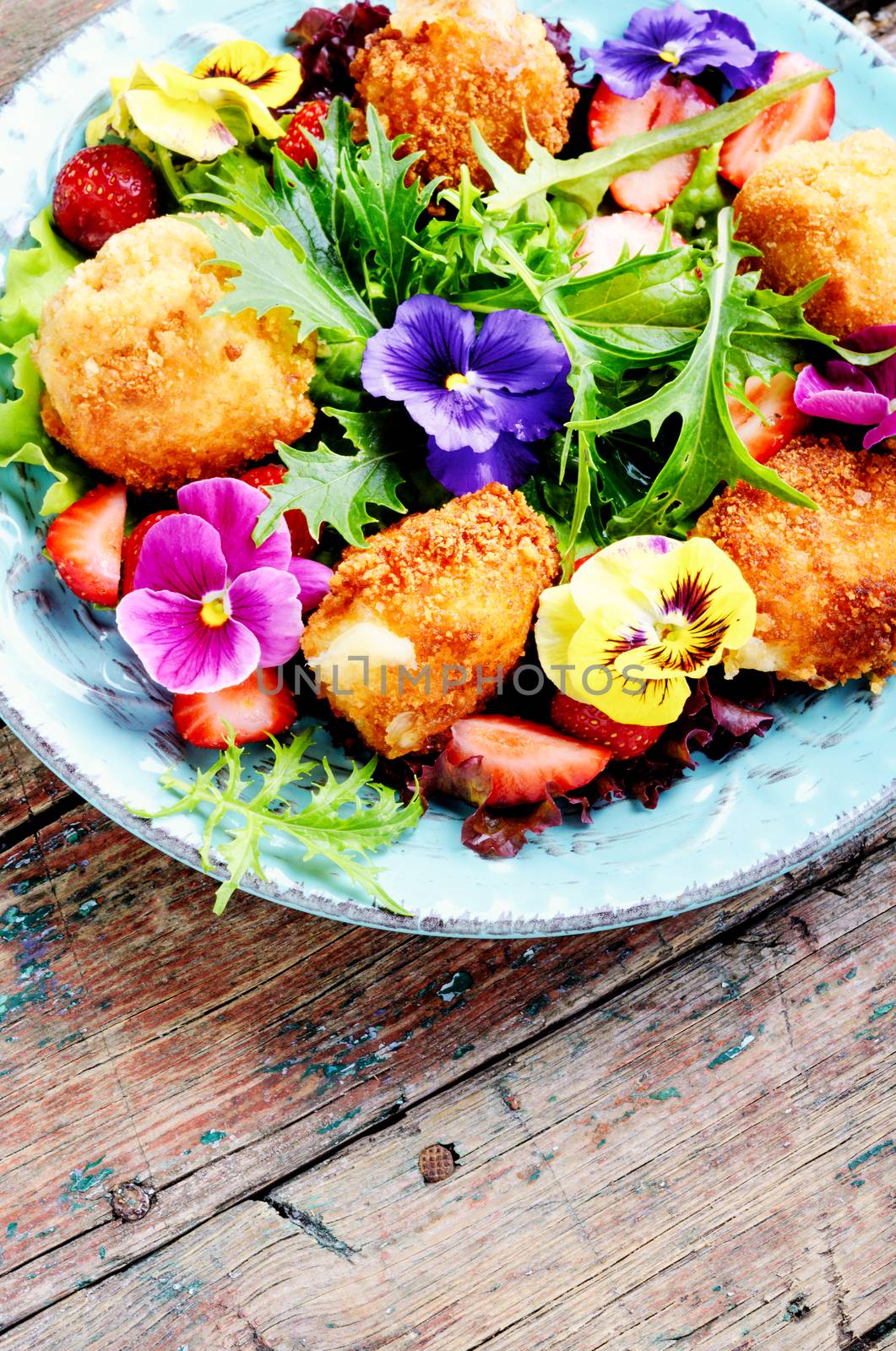 Vitamin summer salad with strawberries, grilled cheese, arugula and flowers.Healthy food