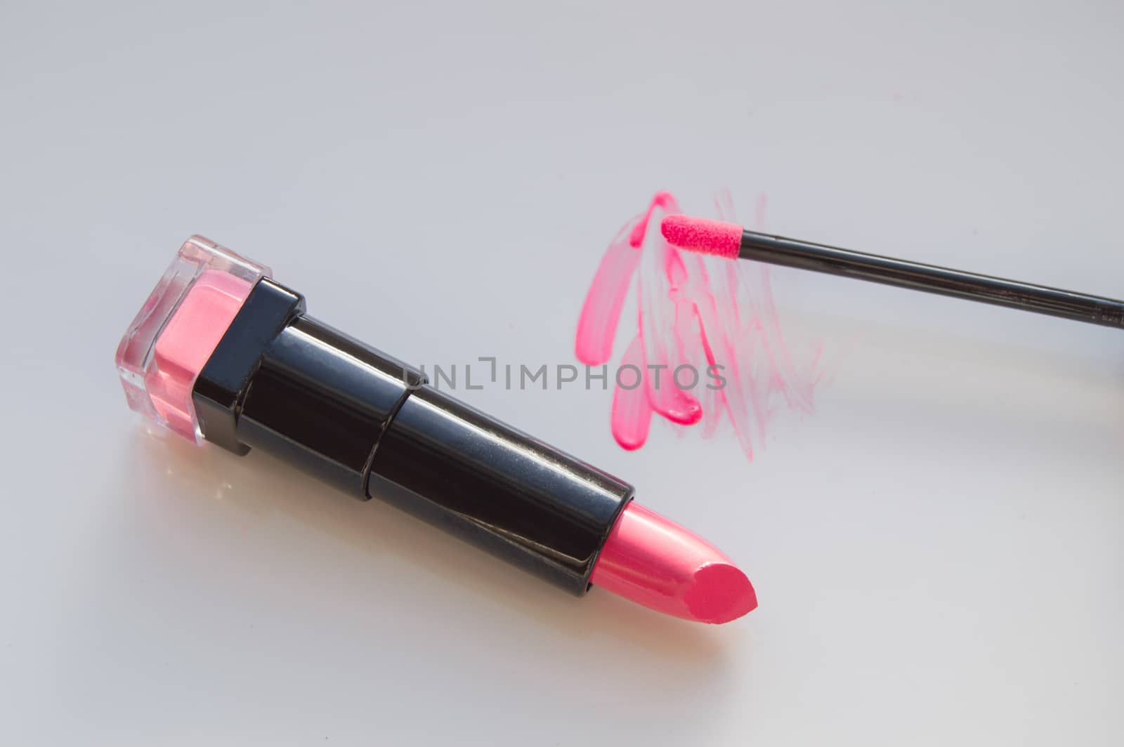 beautiful pink lip gloss smear with brush and a tube of lipstick, white background by claire_lucia