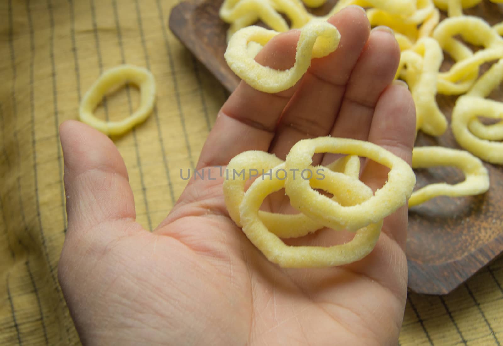 women's hand holding mouthwatering fried onion rings chips.