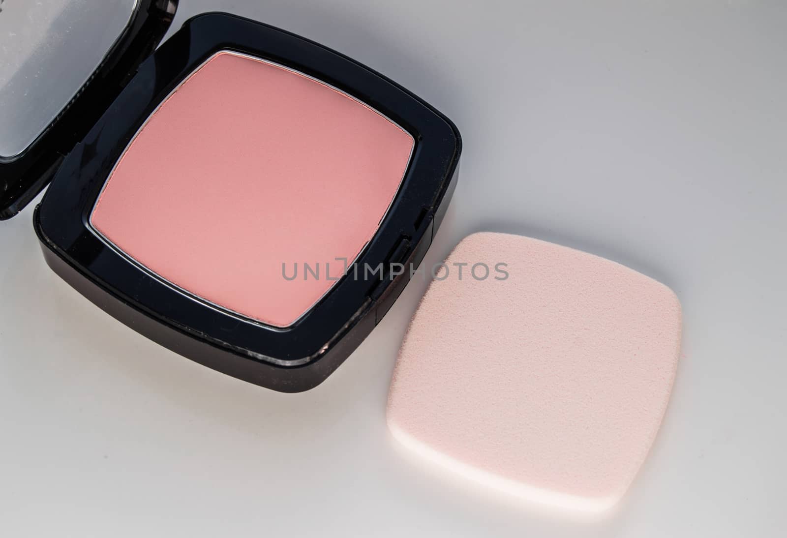 Compact powder with puff for makeup, on white background, top view.