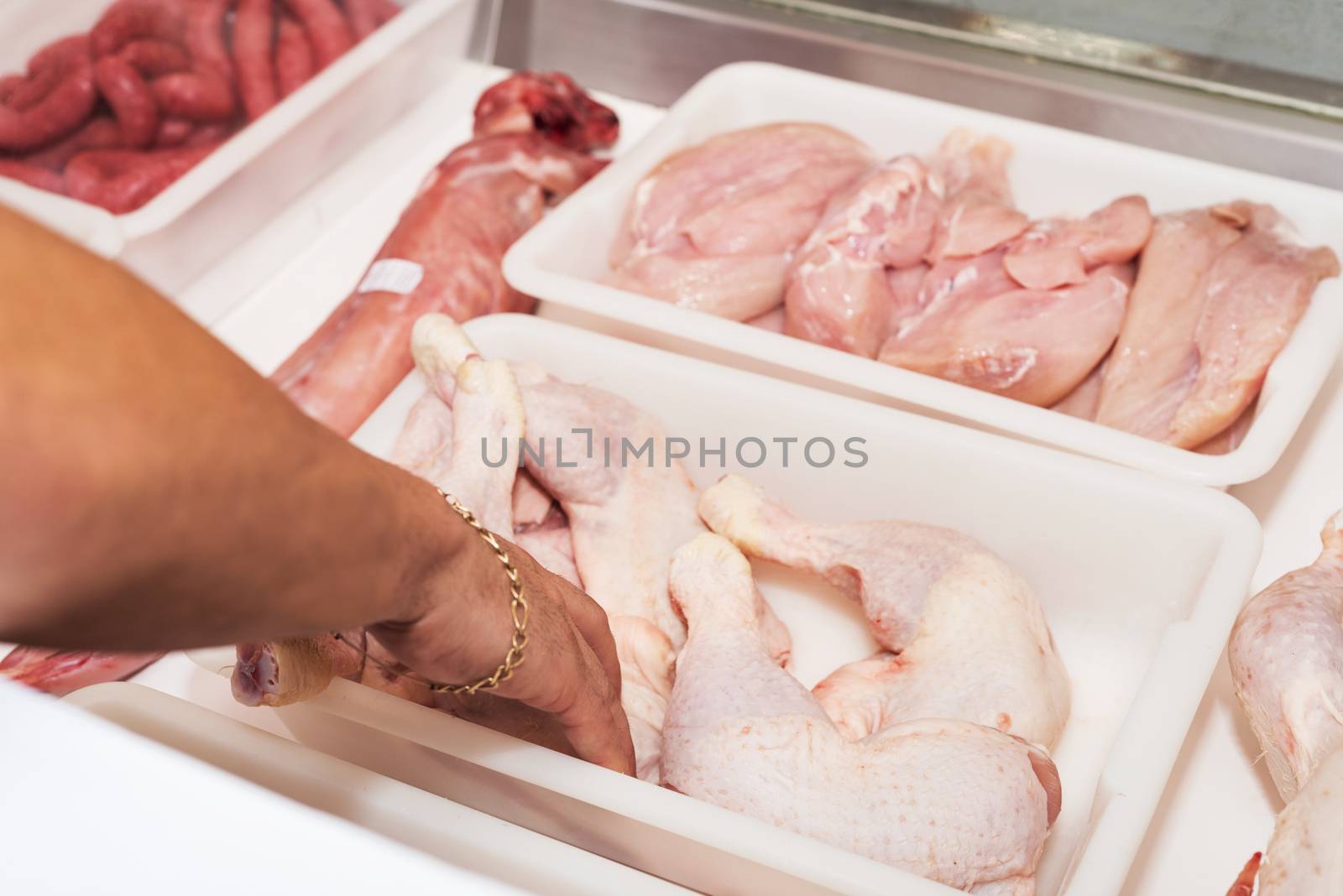 Butcher serving fresh chicken meat at display in butchery by HERRAEZ