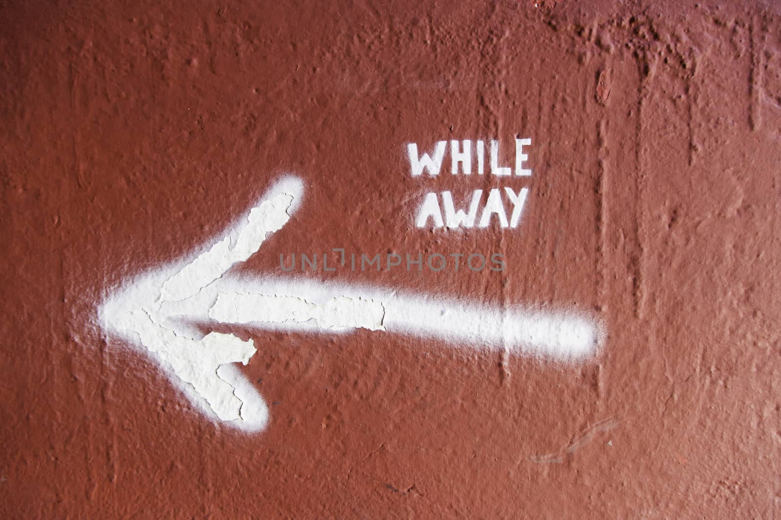 Arrow on a wall with text, detail of an indication, while away