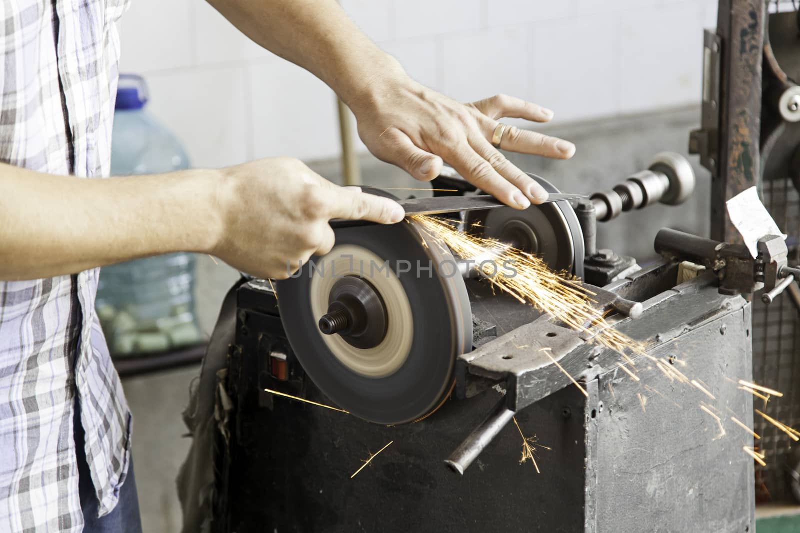 Man sharpening knives, detail of manual work, sparks